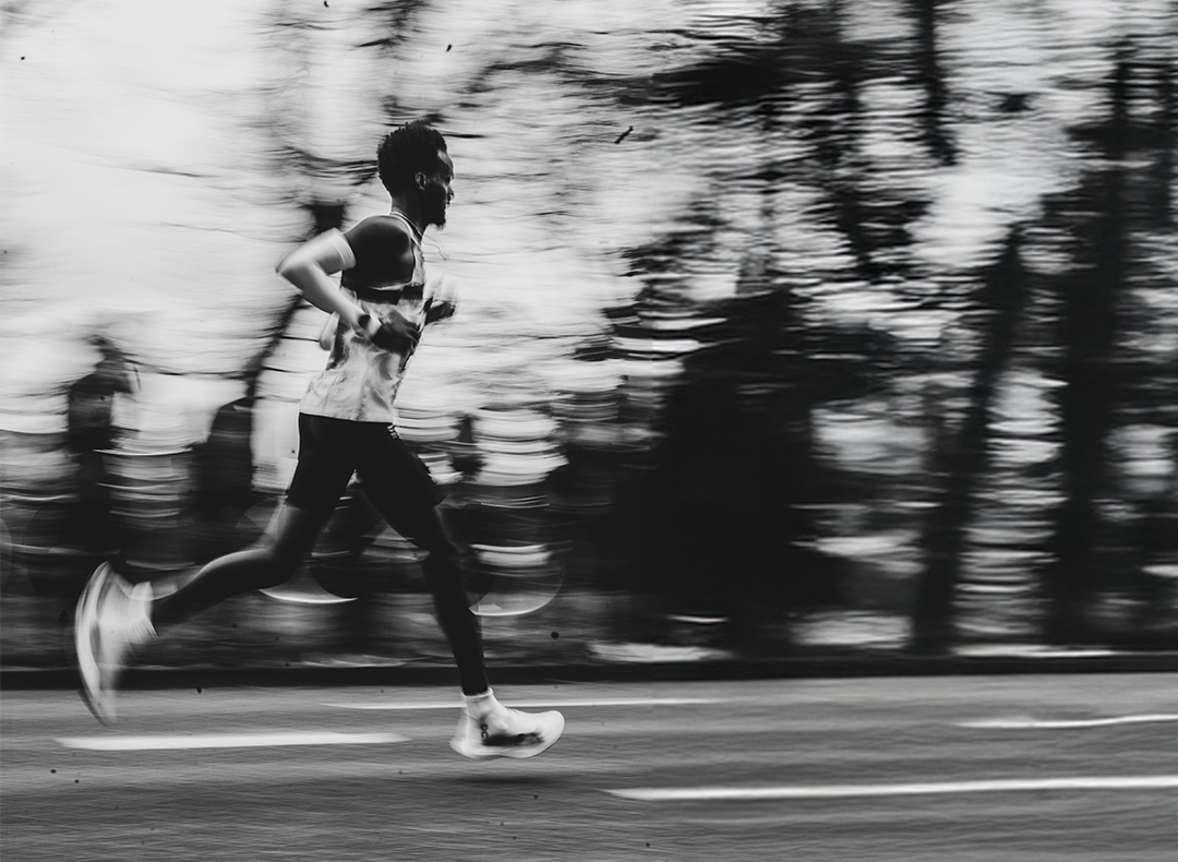 Black and white photo of a person running on a track with blurred background