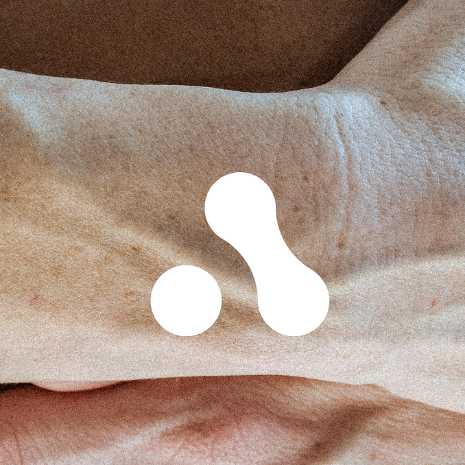 Close-up of a person's wrist with a white abstract design on brown skin.